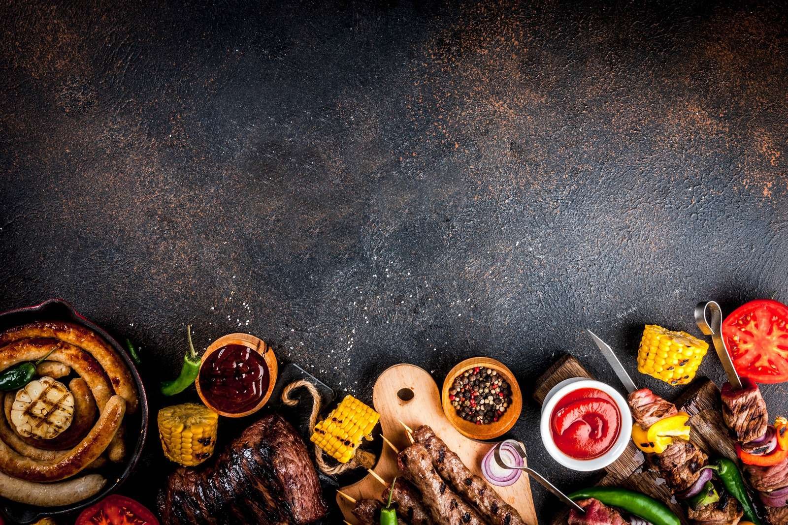 Assortment various barbecue food grill meat, bbq party fest - shish kebab, sausages, grilled meat fillet, fresh vegetables, sauces, spices, dark rusty concrete table, above copy space